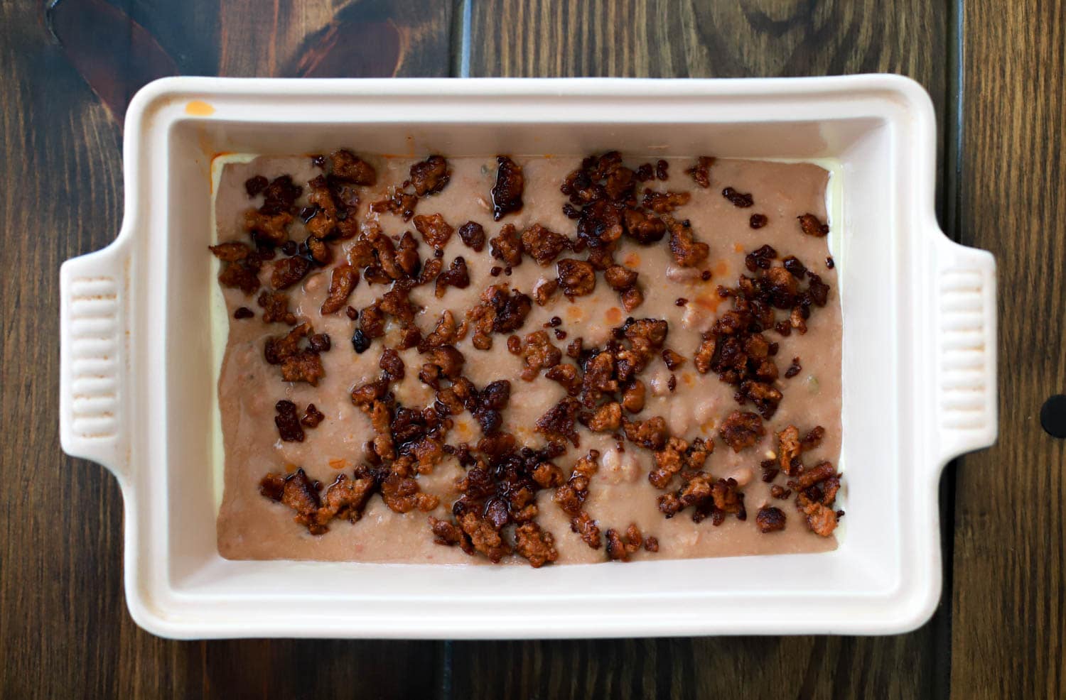 rectangular baking dish with layer of beans and chorizo for dip.