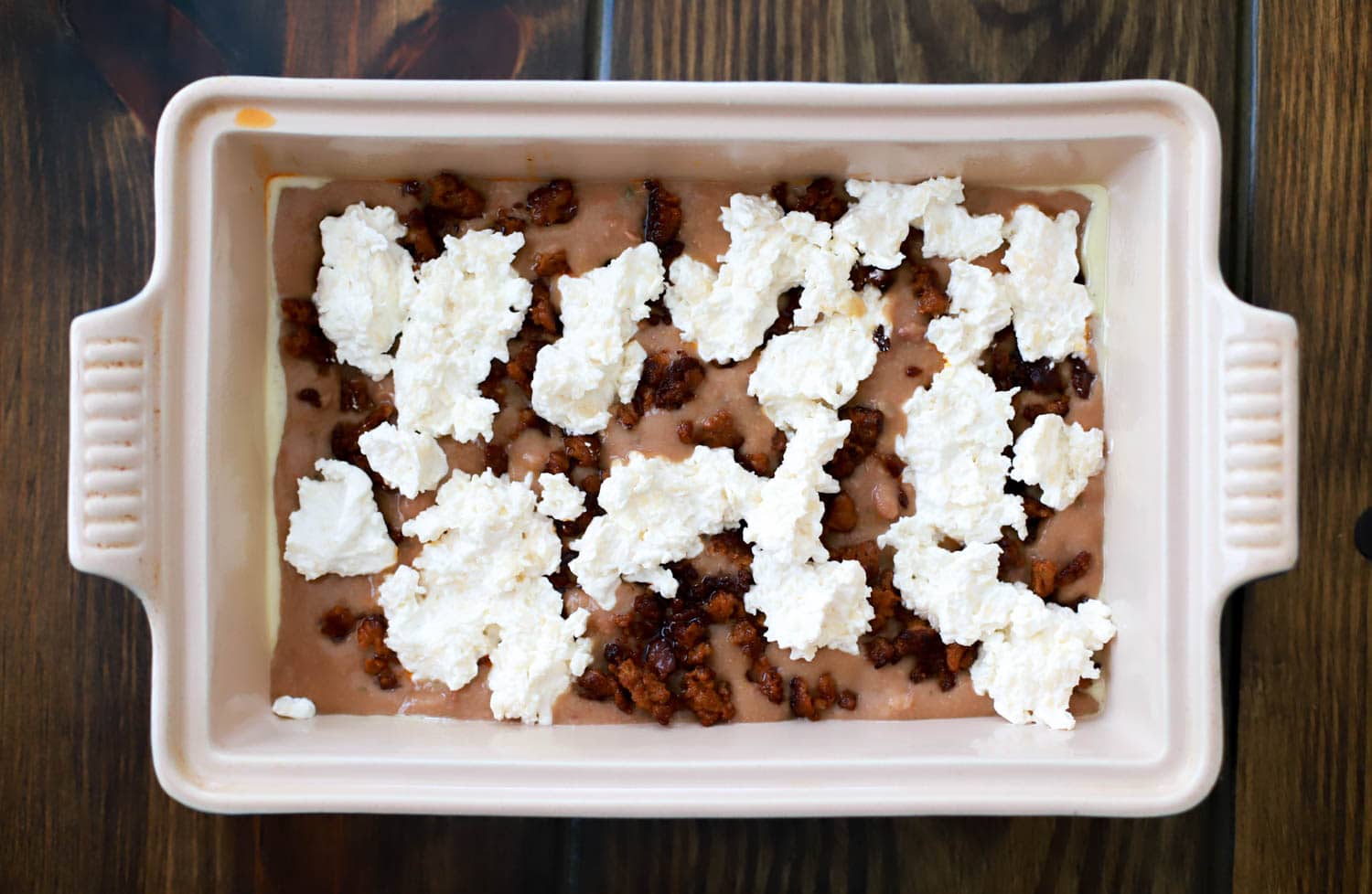 rectangular baking dish with layer of beans topped with sour cream for dip.