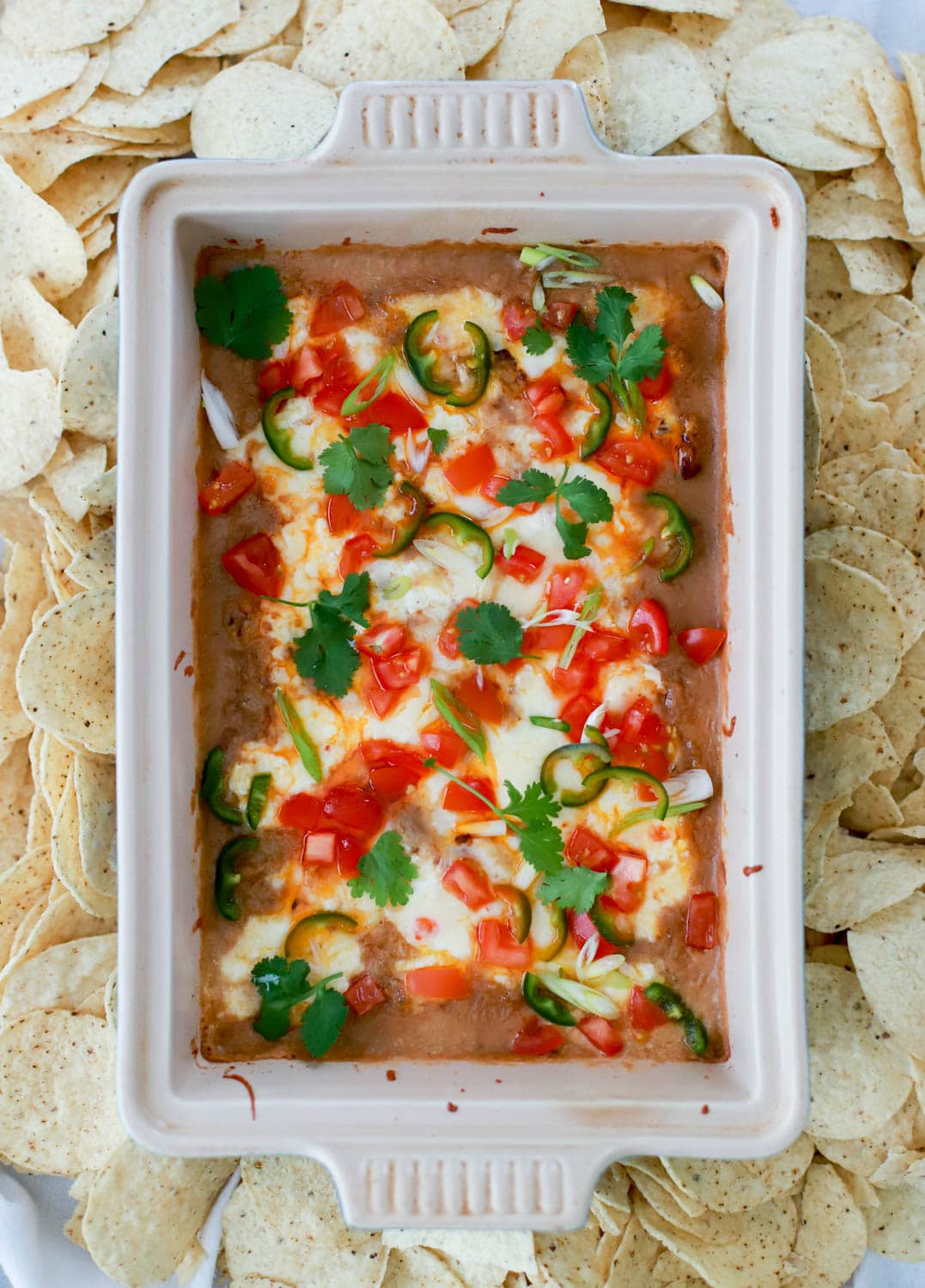 large baking dish with hot bean dip surrounded by chips.