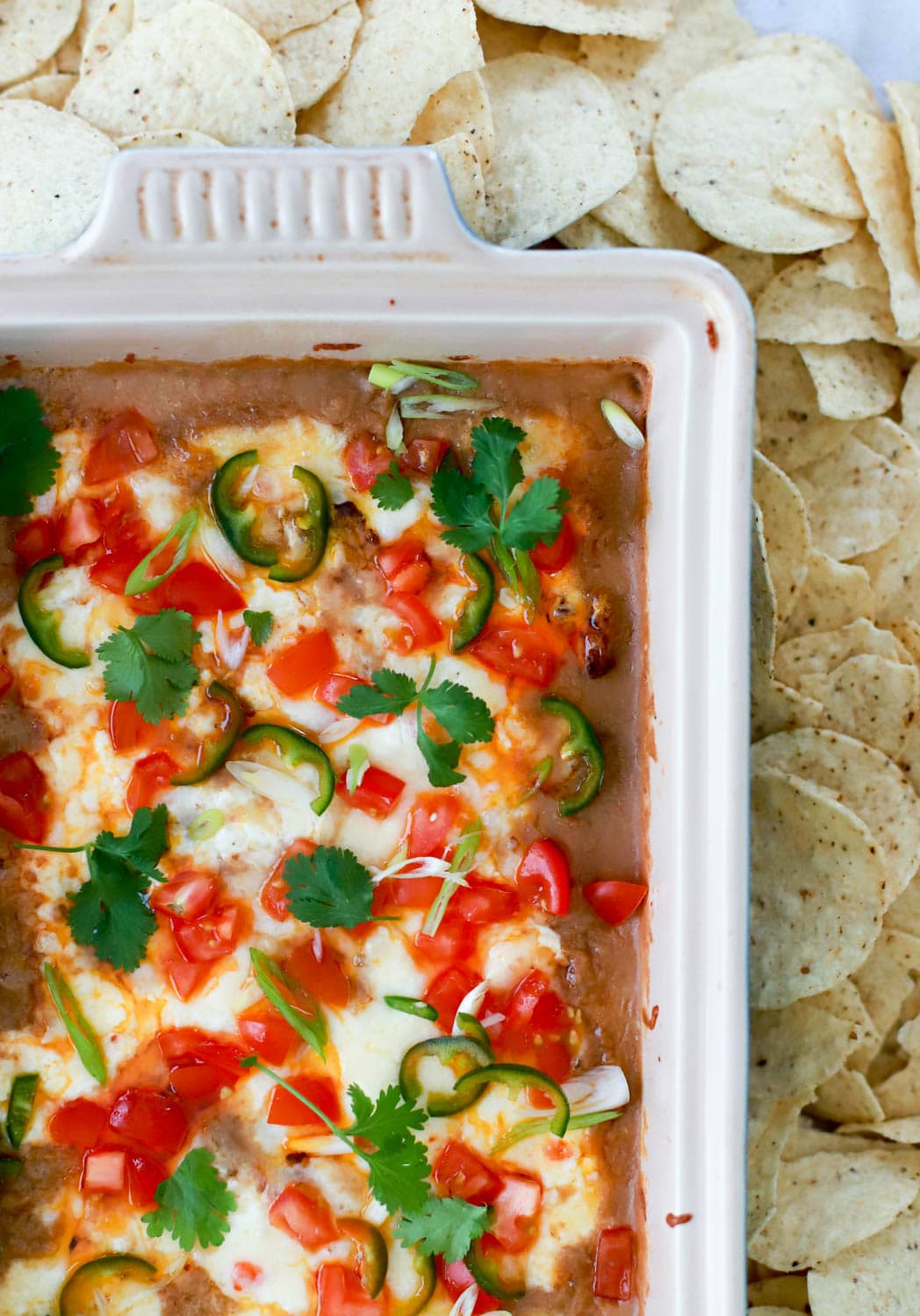 Close up top view of refried bean dip with tortilla chips for dipping.