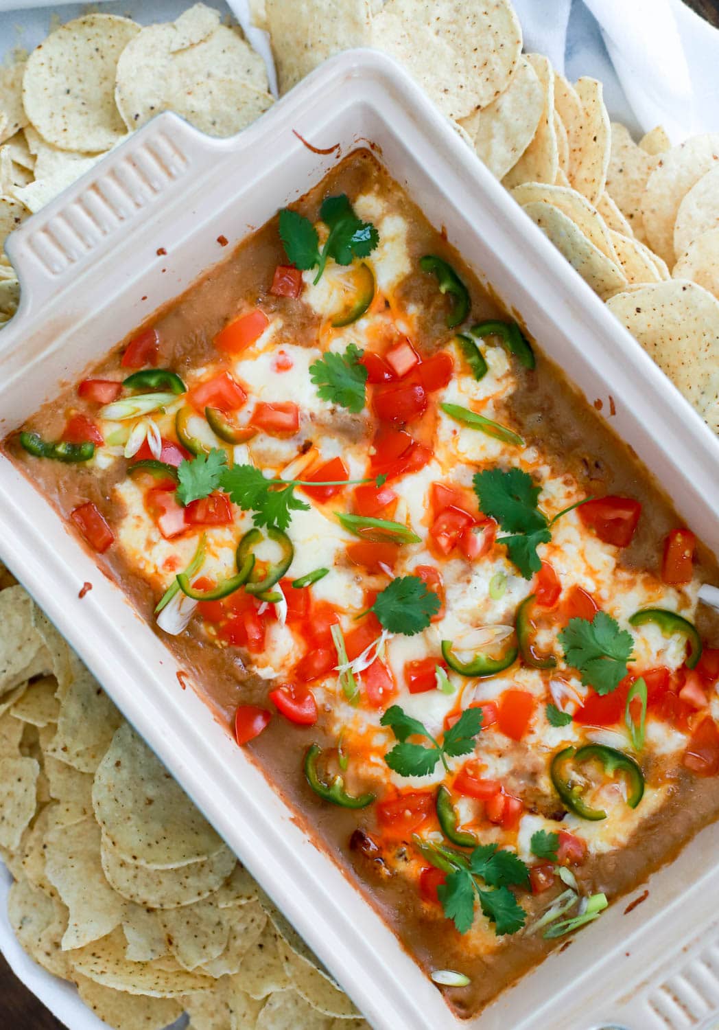 rectangular baking dish of cheesy bean dip surrounded by chips.