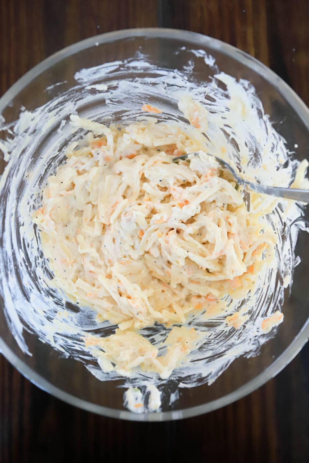 ingredients for make ahead hashbrown casserole stirred together in glass bol