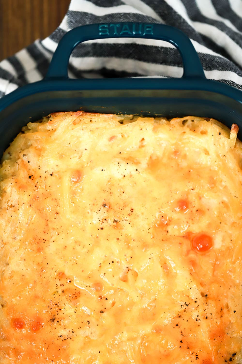 top view of cheesy hash brown casserole in dark green baking dish.