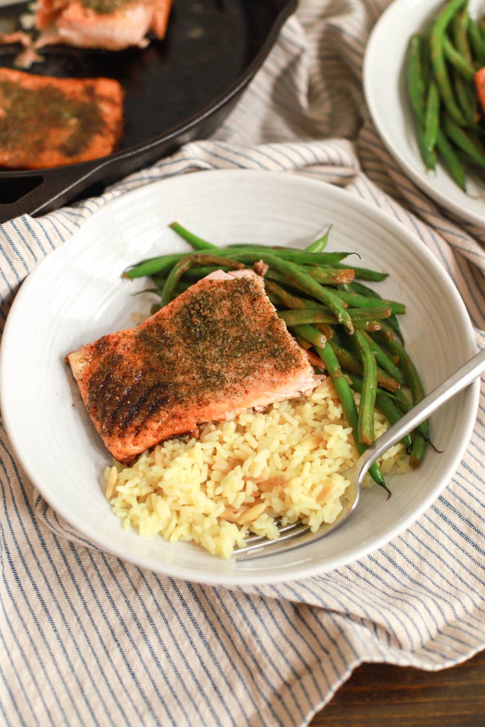 pan seared salmon with skin in white bowl with rice and green beans