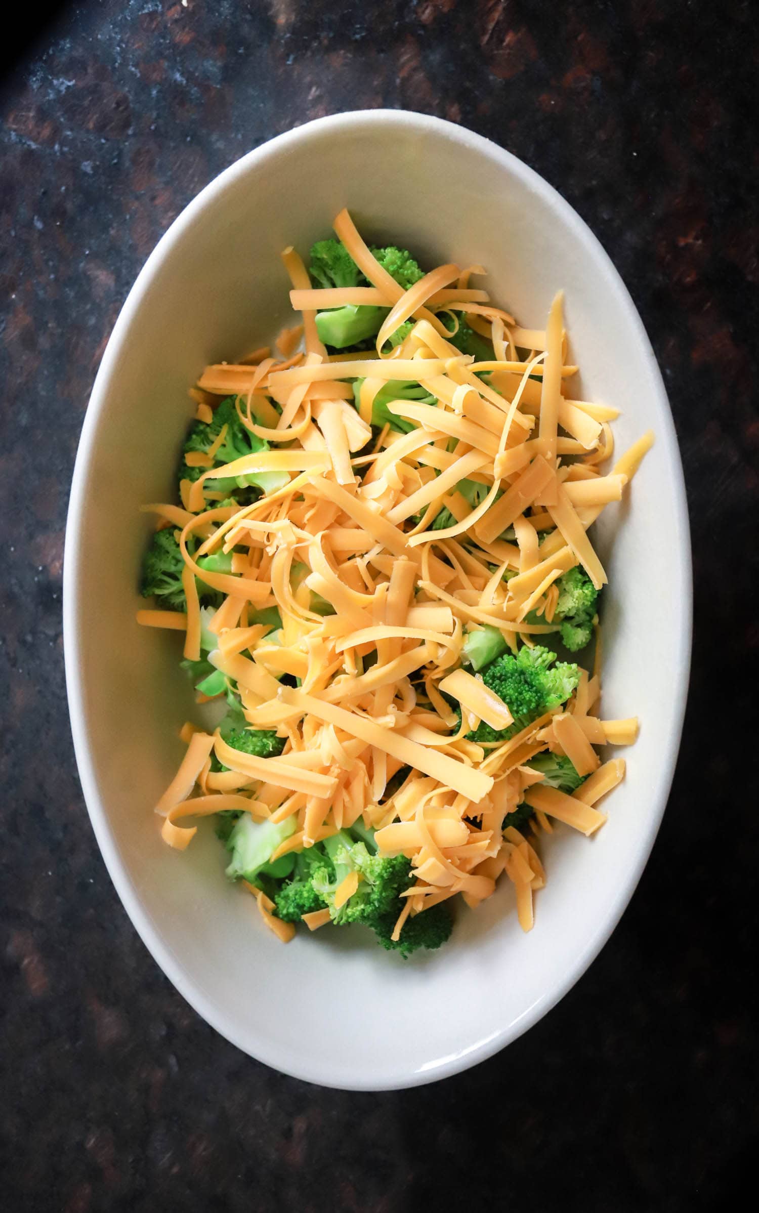 top view of raw broccoli with grated cheddar over top.