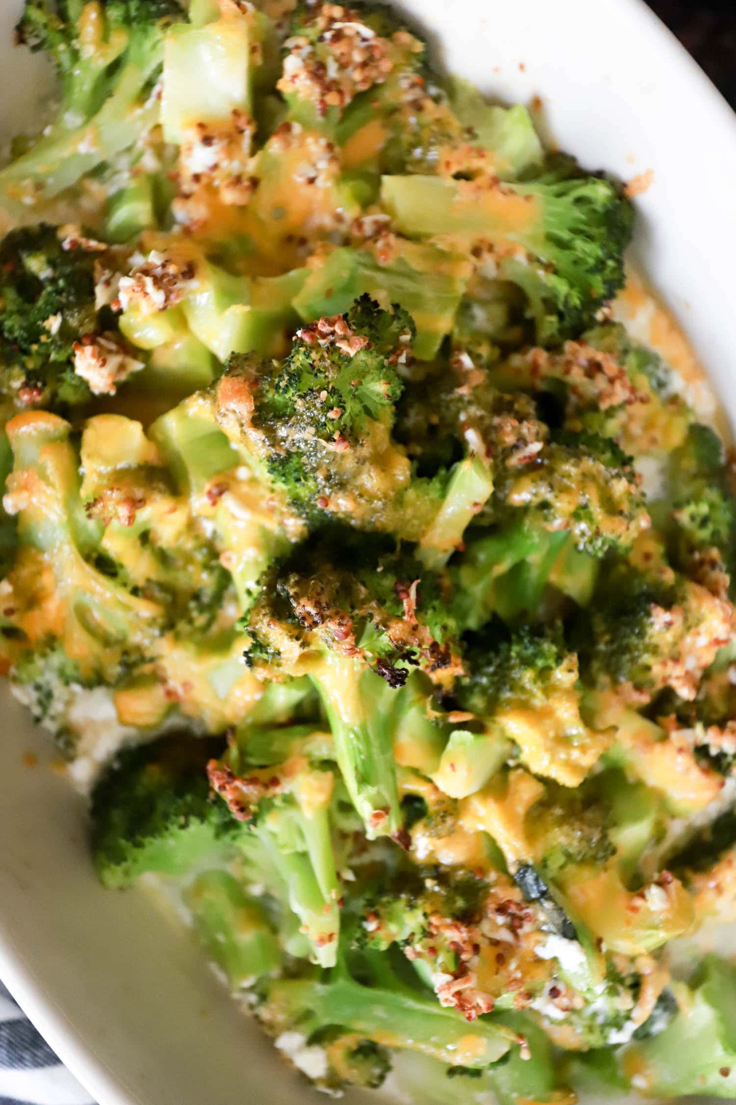 cheesy baked broccoli close up with texture of grainy mustard.