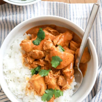 indian butter chicken served with rice in a white bowl.