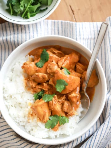 indian butter chicken served with rice in a white bowl.