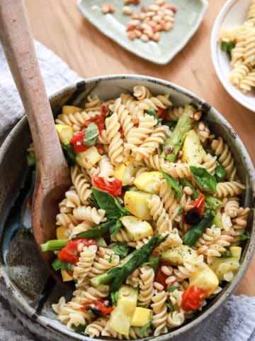 bowl of pasta salad with veggies and wooden spoon