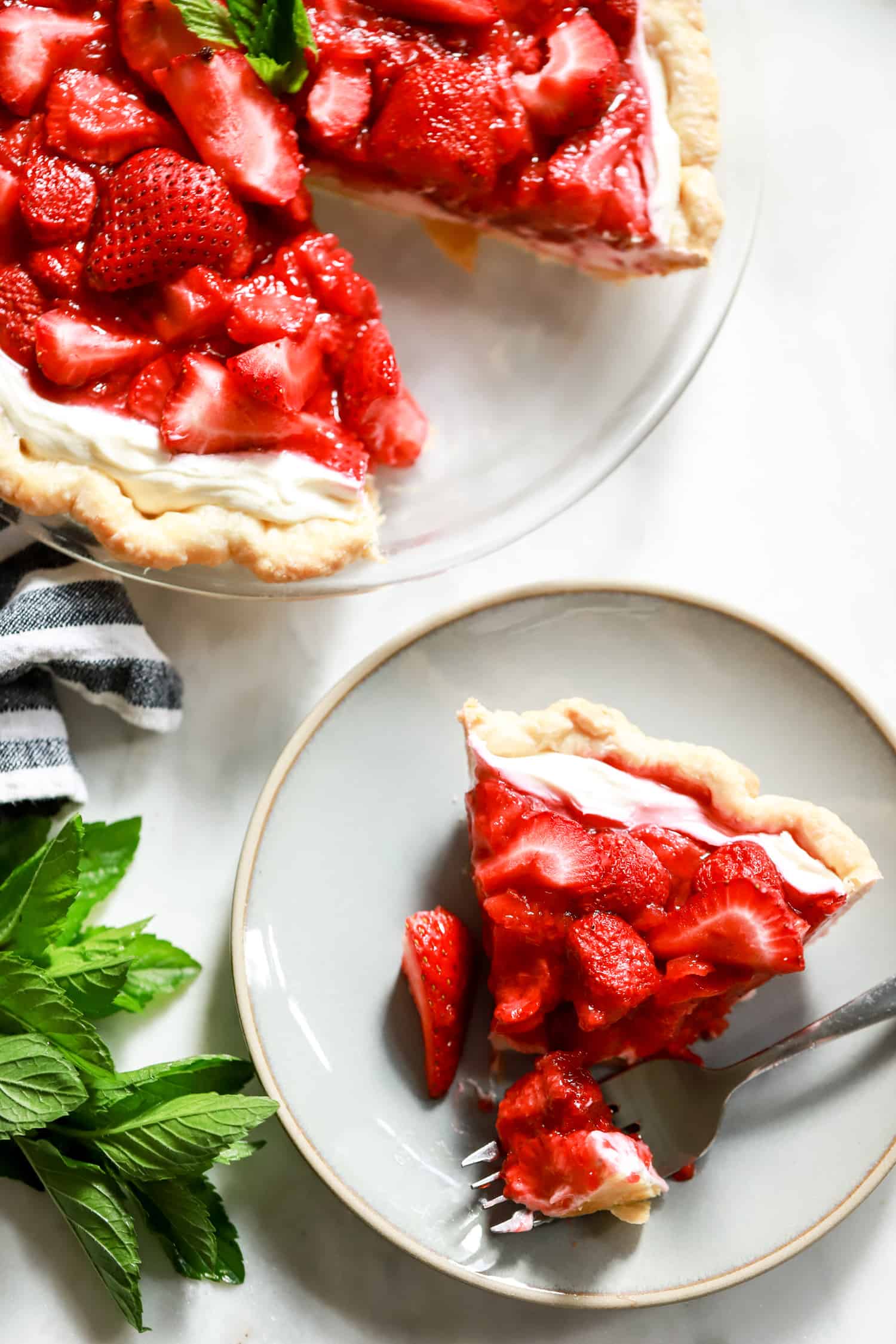flatlay strawberry pie with cream cheese slice on plate with bite taken out.
