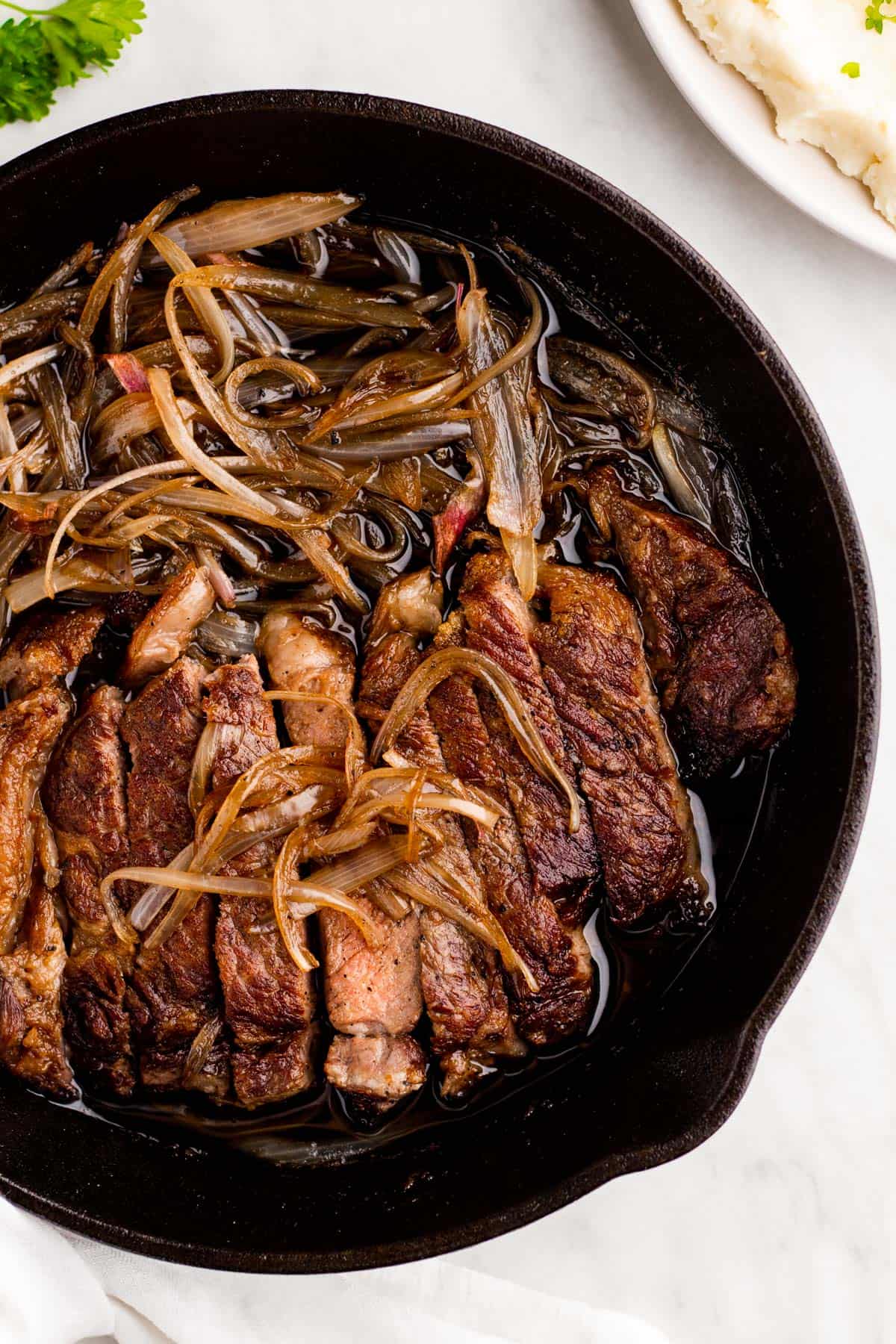 Black skillet with steak and shallots ready to be served.