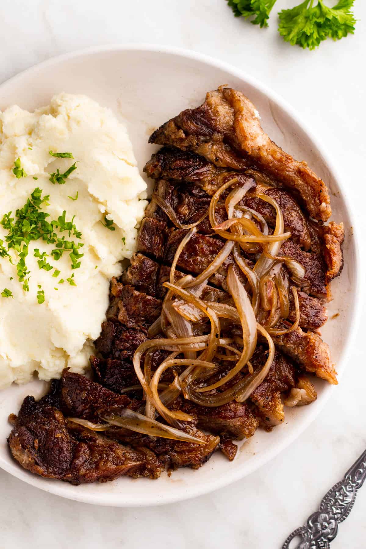 White plate with steak and mashed potatoes.