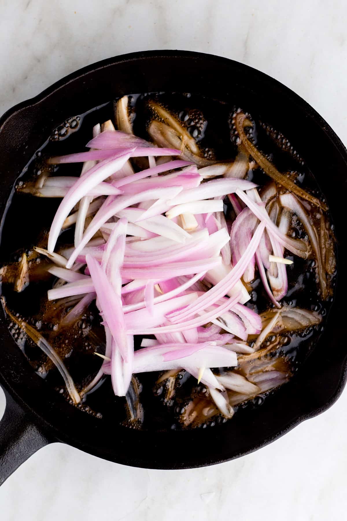 Raw sliced shallots in cast iron skillet.