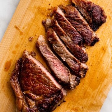 Sliced NY Strip on light wooden board.