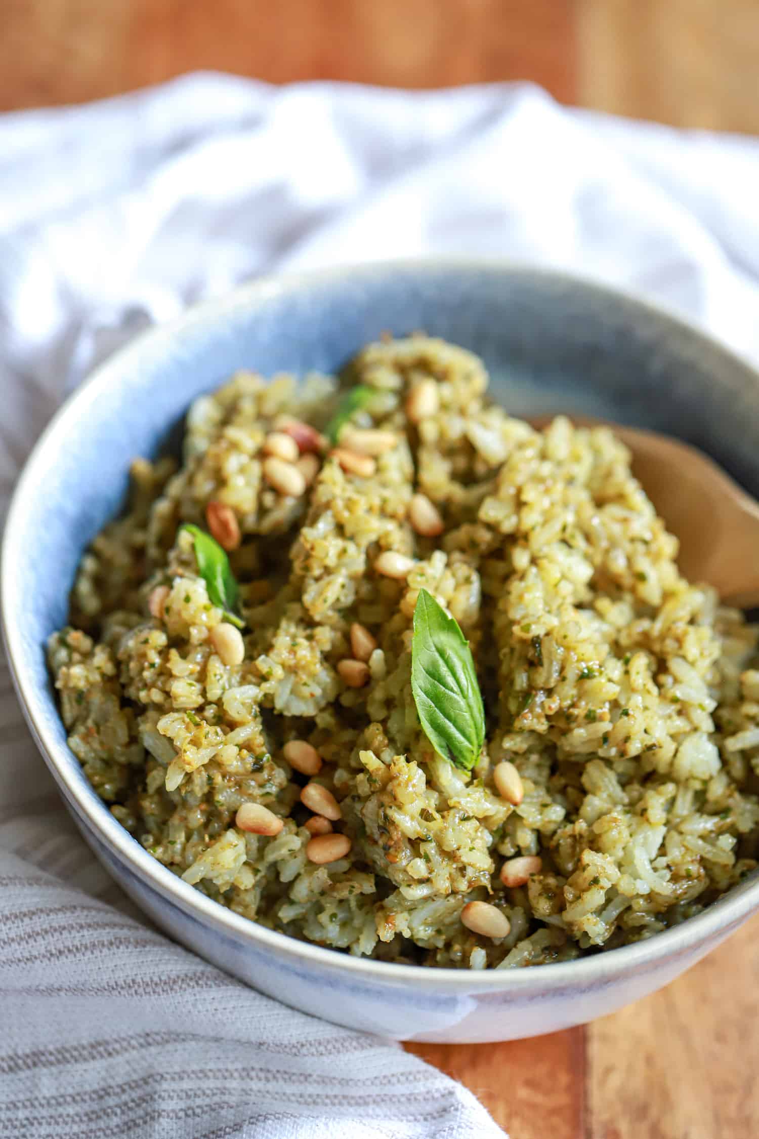 blue bowl filled with pesto rice on wooden board with napkin