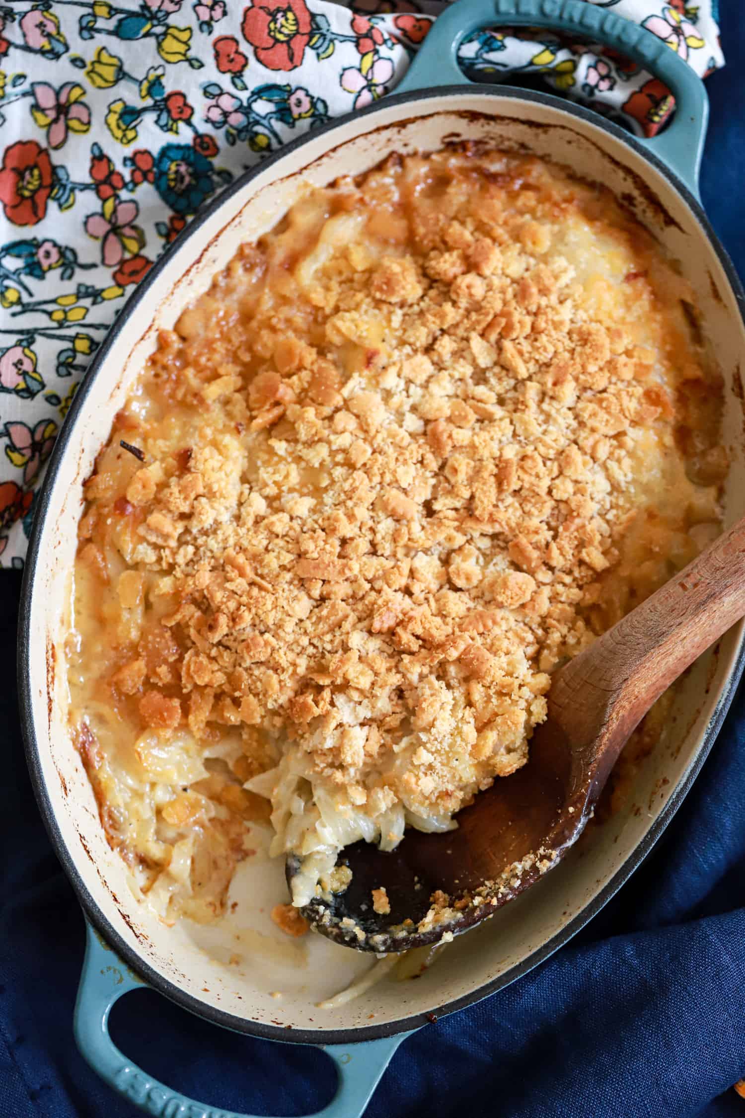 sweet onion casserole with wooden spoon and floral napkin in background.