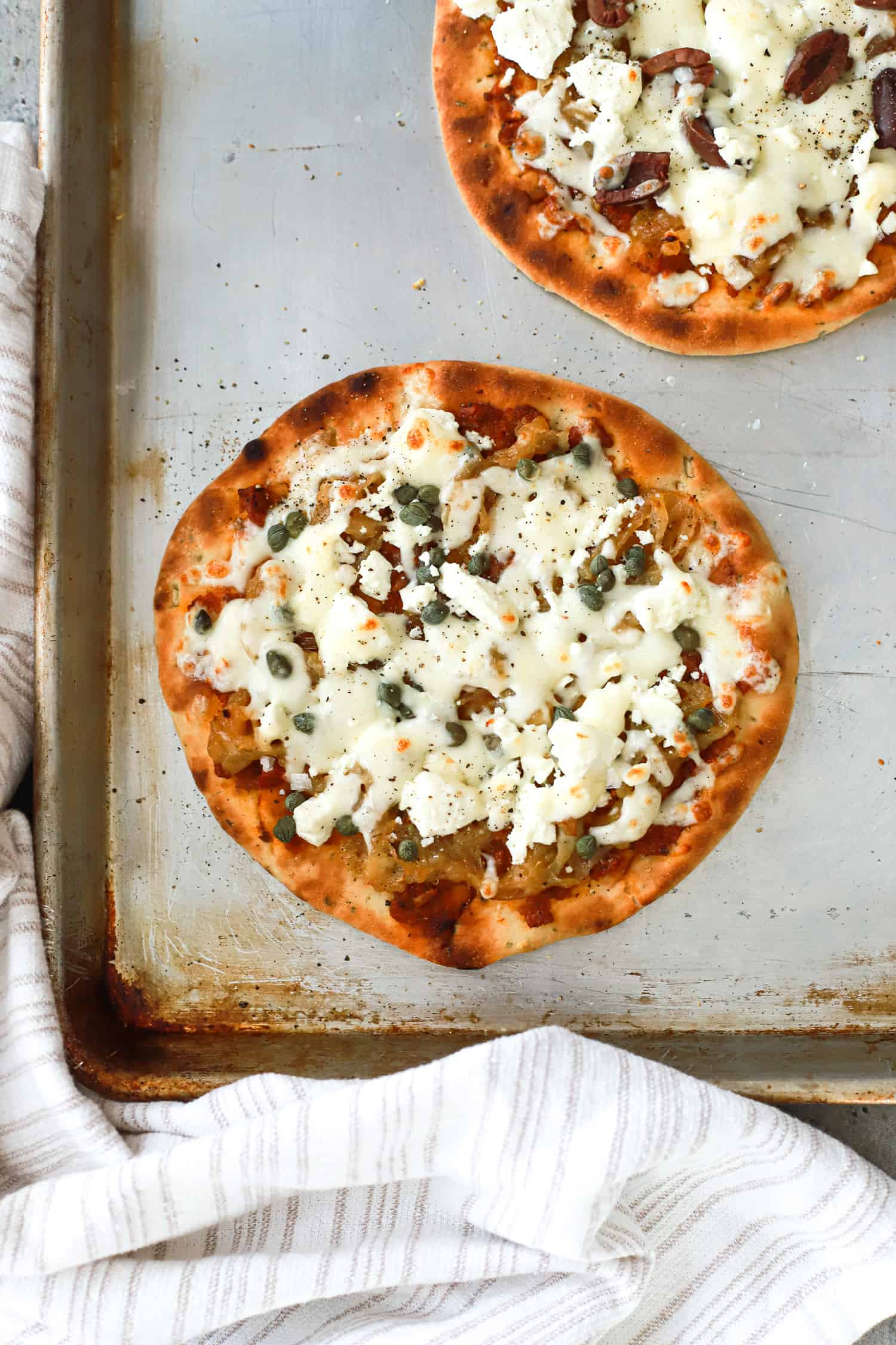 close up top view of goat cheese flatbread with capers.