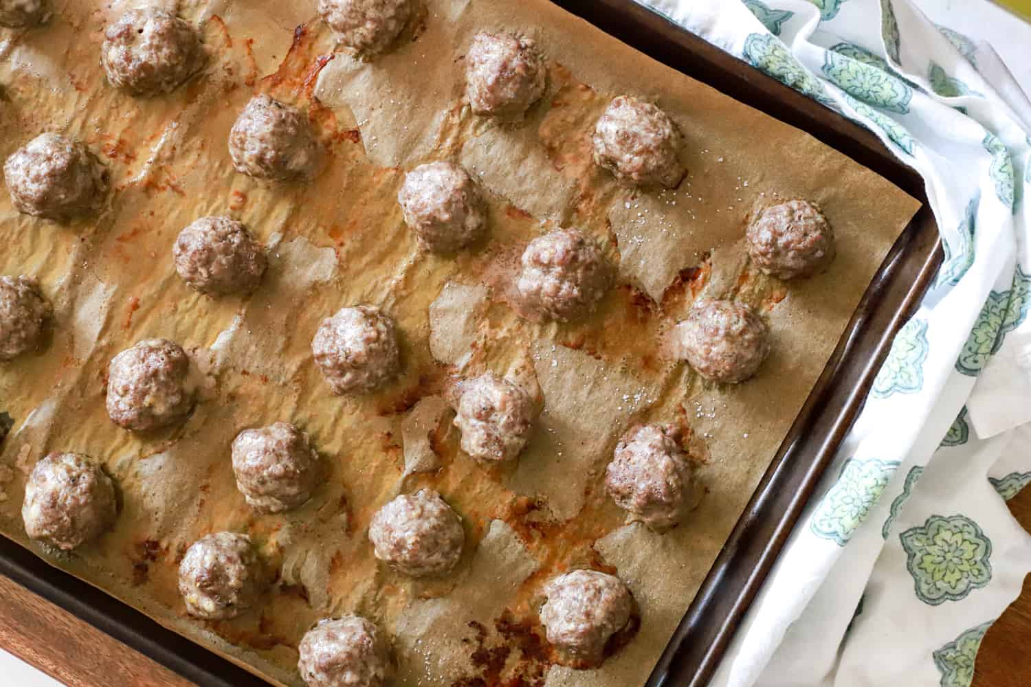 baking sheet with roasted greek meatballs on parchment paper.