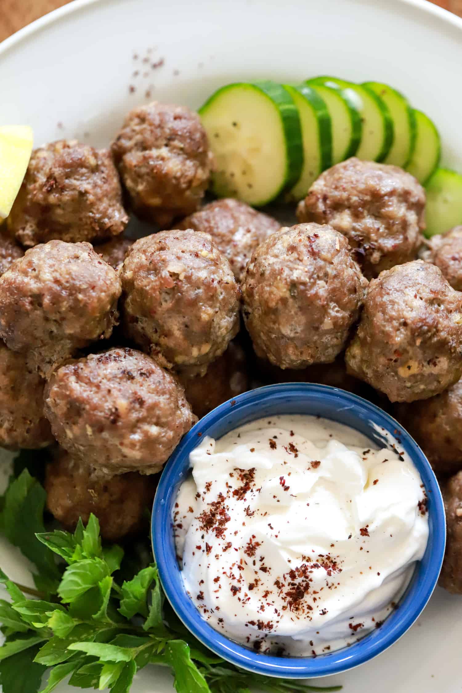 greek meatballs with tzatziki sauce and cucumbers on a plate.