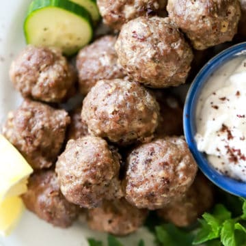 pile of greek meatballs with cucumber slices and fresh mint.
