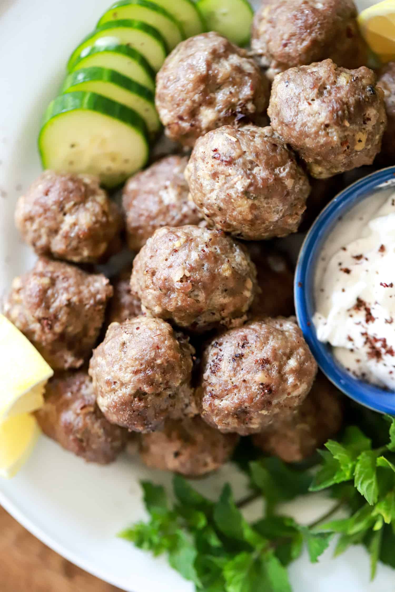 pile of greek meatballs with cucumber slices and fresh mint.