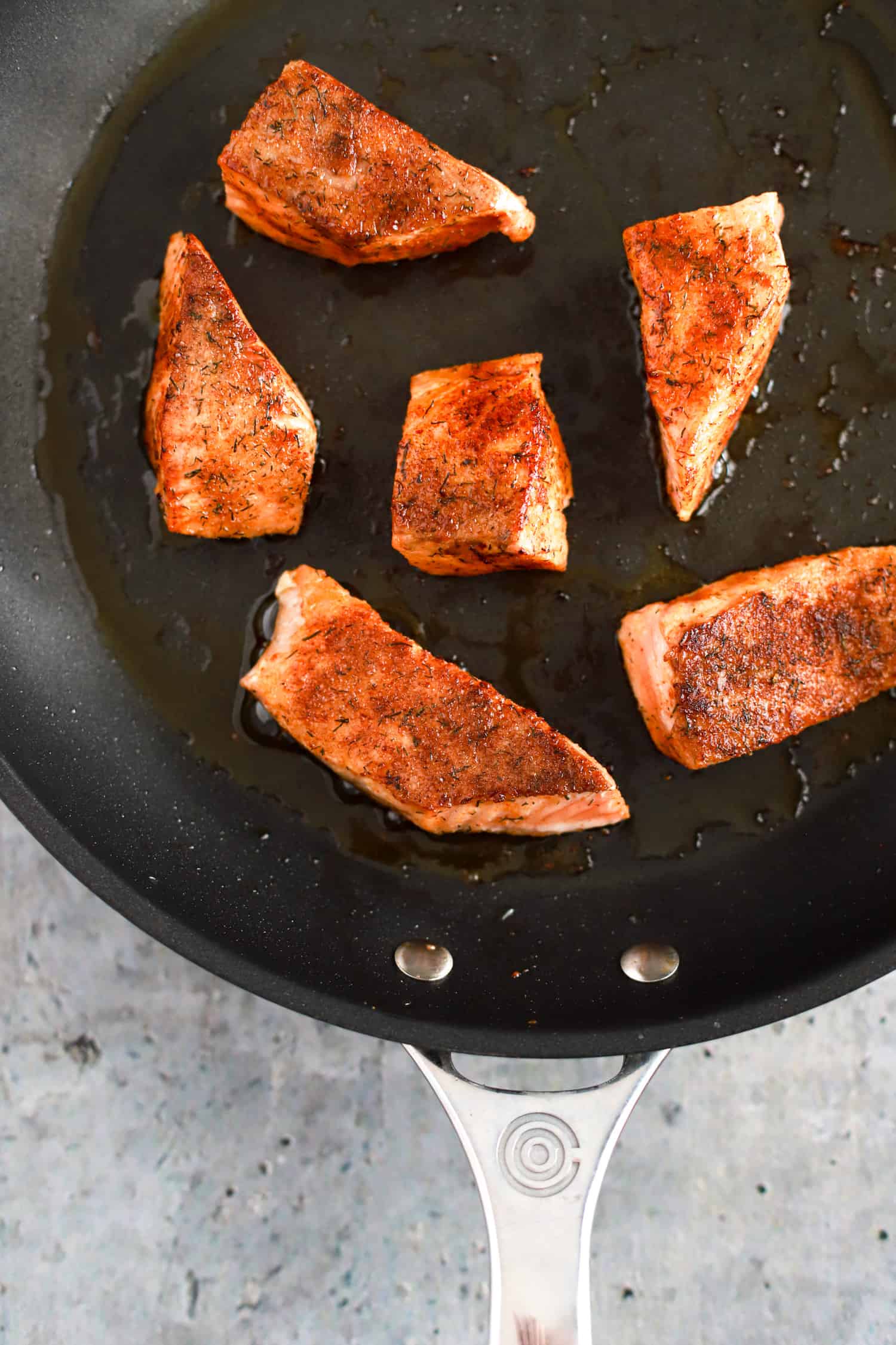 black skillet with seared salmon pieces.