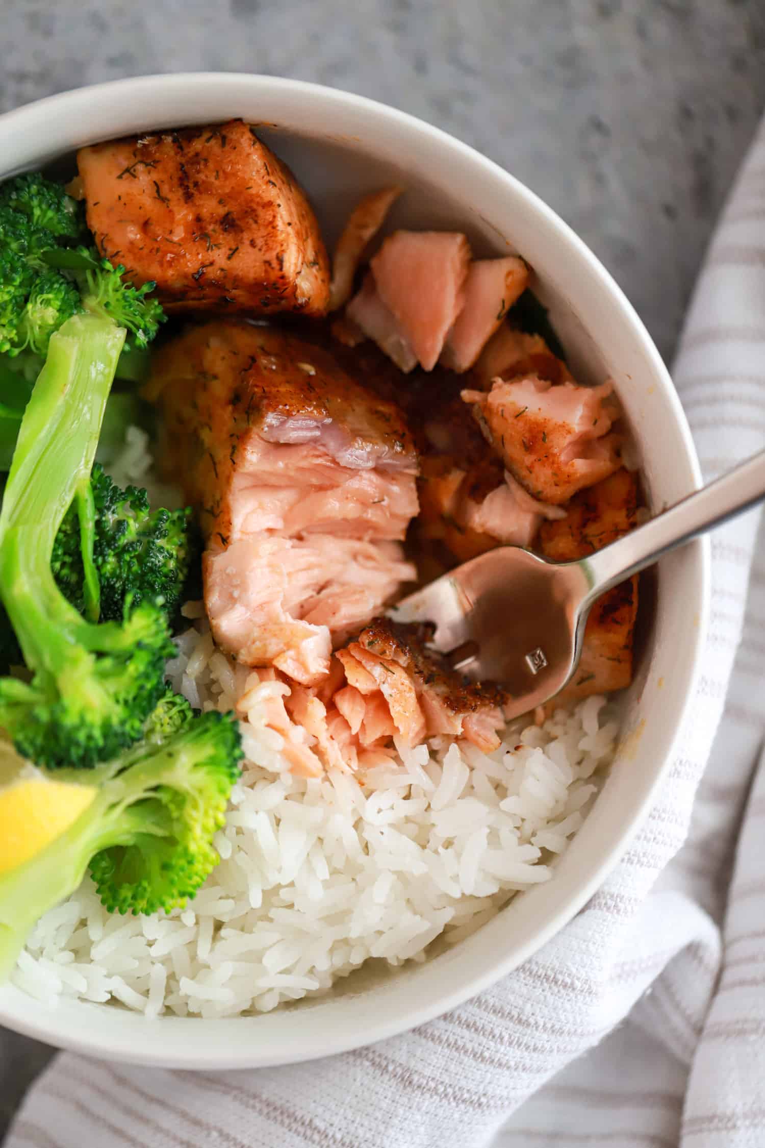 close up flaked salmon over rice with broccoli.