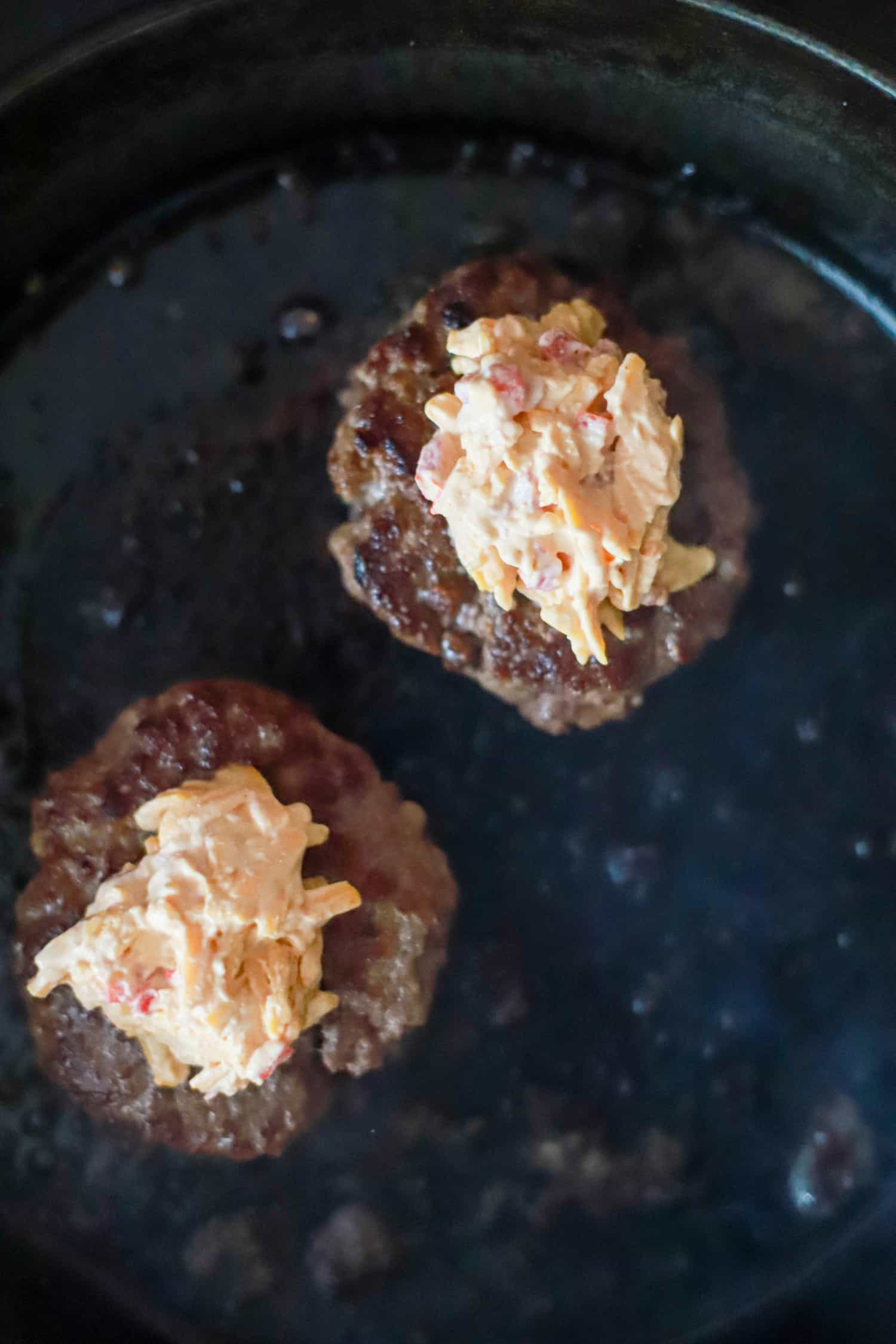 cast iron skillet smashburgers topped with pimento cheese.