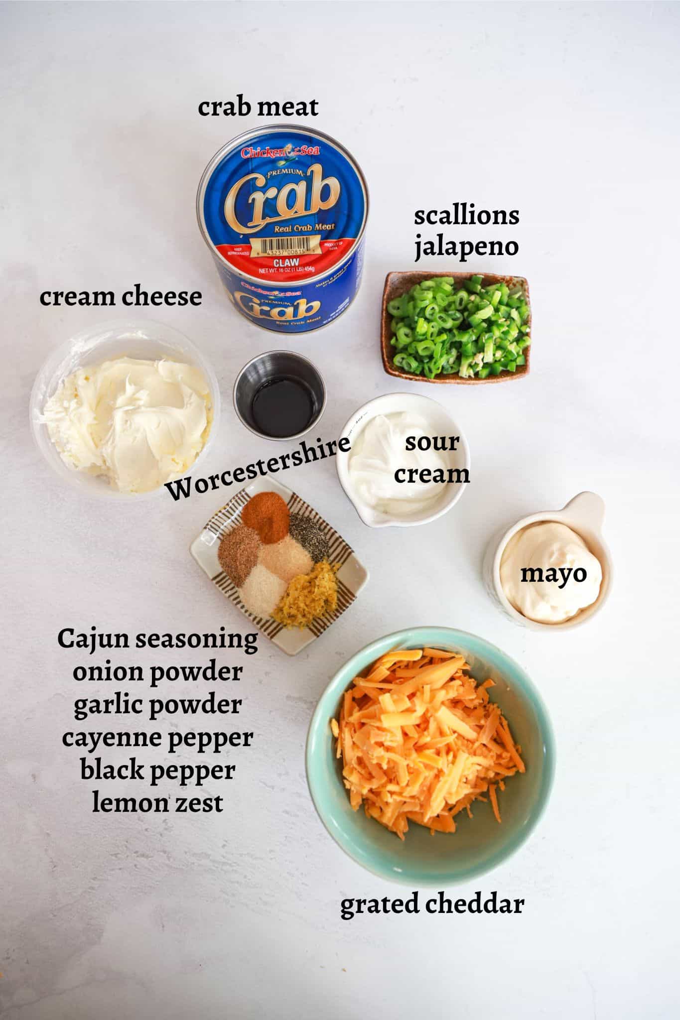 Ingredients for hot cajun crab dip on a white board with black text labels.
