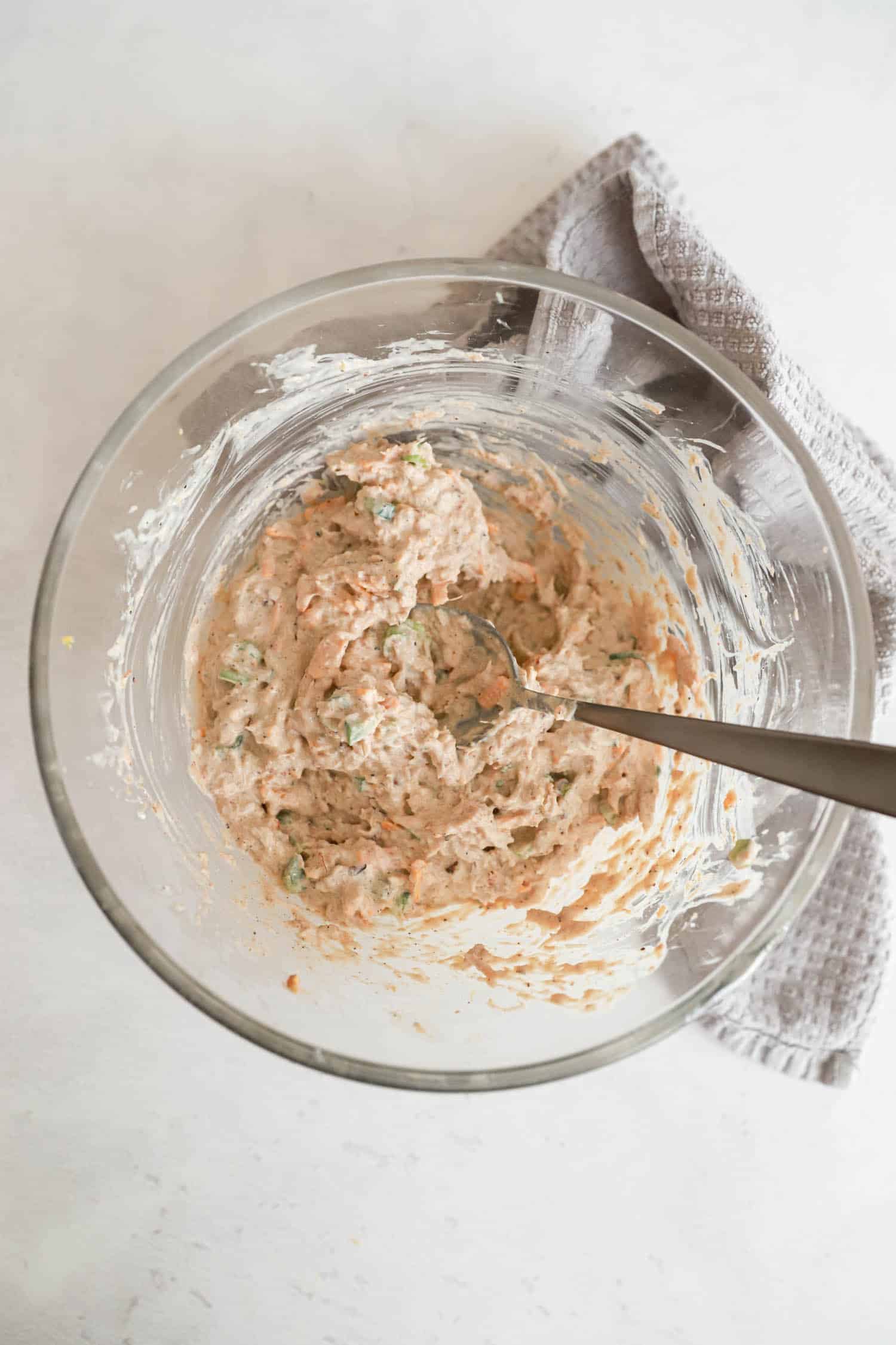 Unbaked crab dip stirred together in glass mixing bowl.