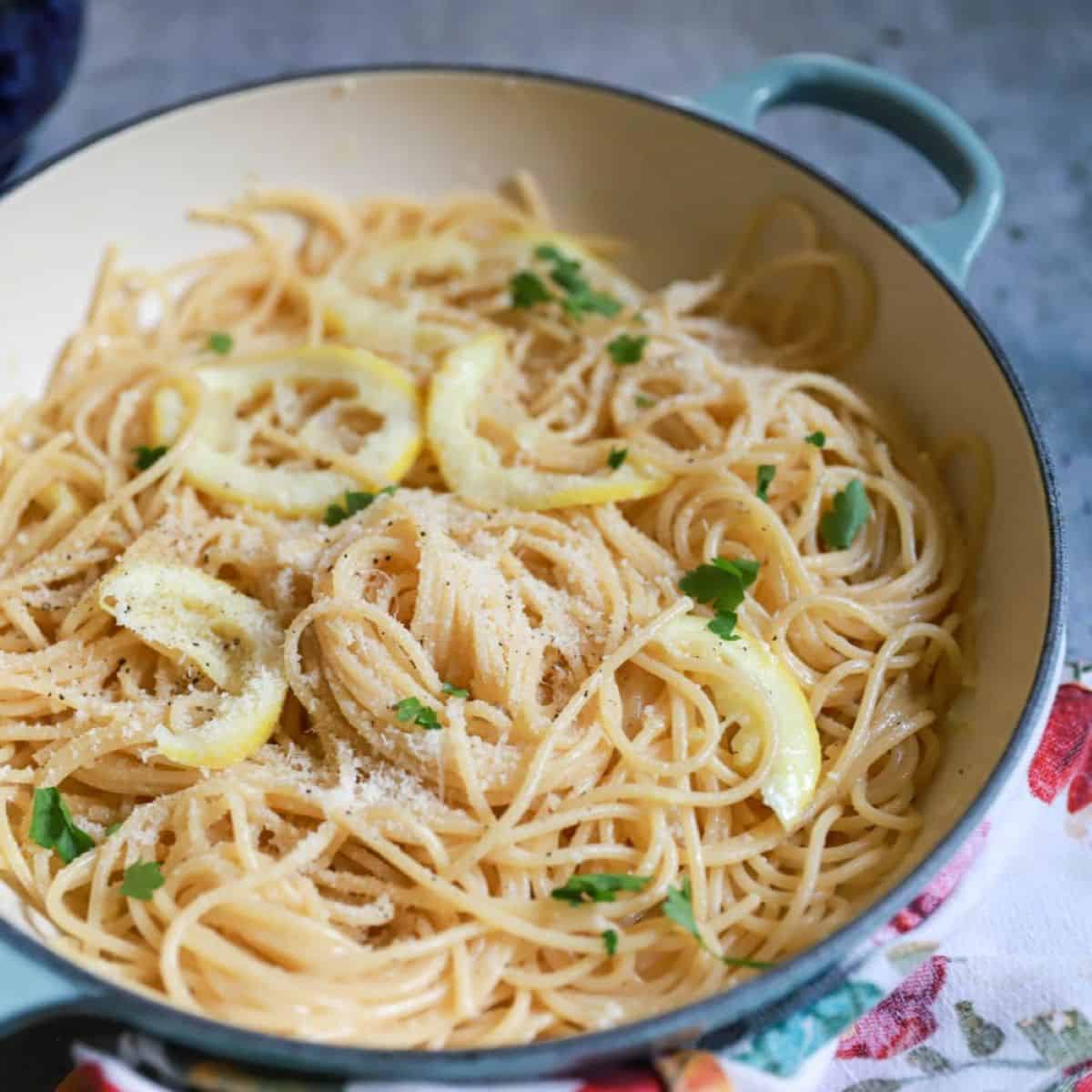 Blue round skillet of lemon garlic butter pasta with fresh parsley on top.