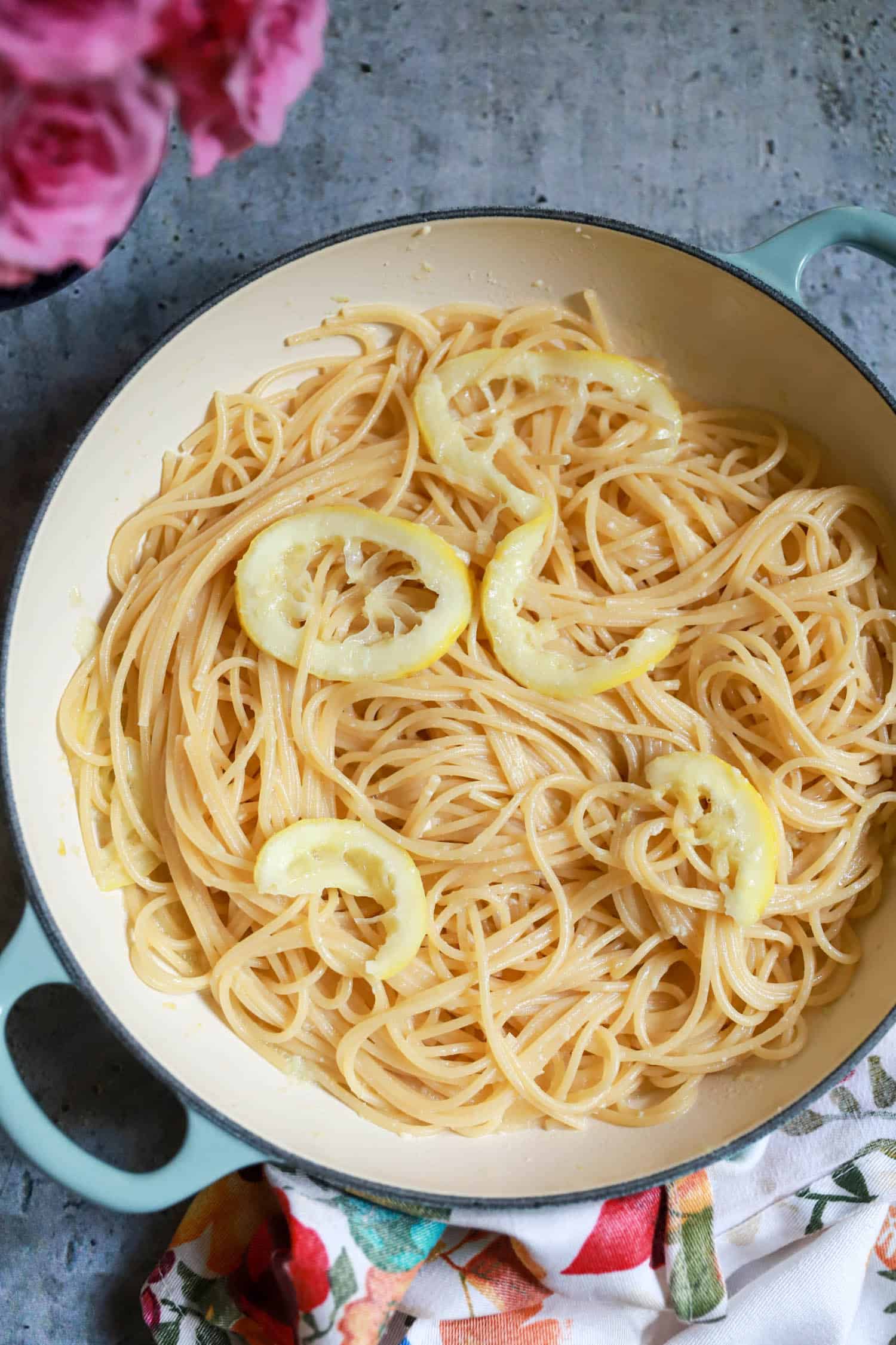 Spaghetti swirled with fresh lemon slices on a gray background.