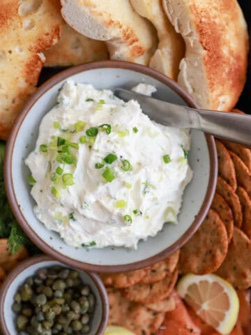 Small white bowl of cream cheese and scallions.