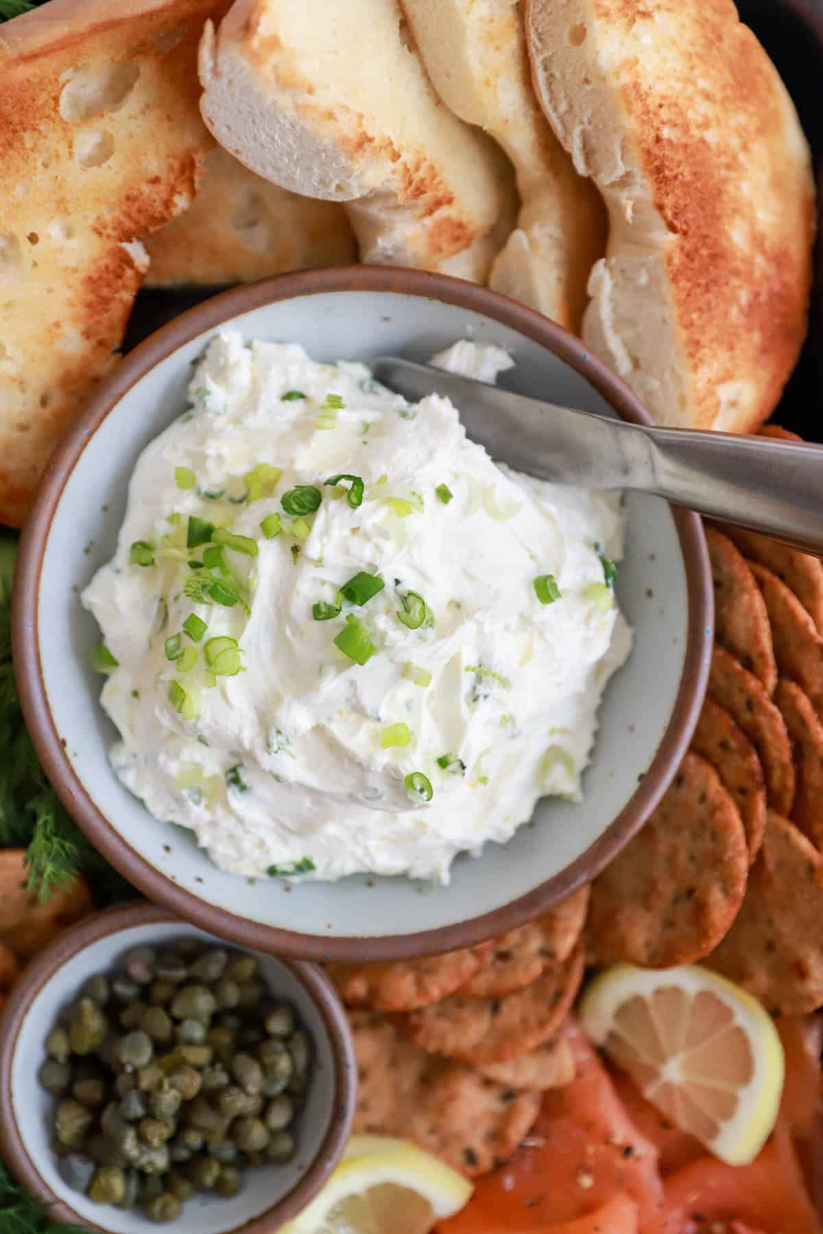Small white bowl of cream cheese and scallions.