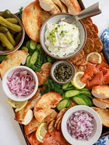 Smoked salmon charcuterie board with scallion cream cheese and pickled red onions.