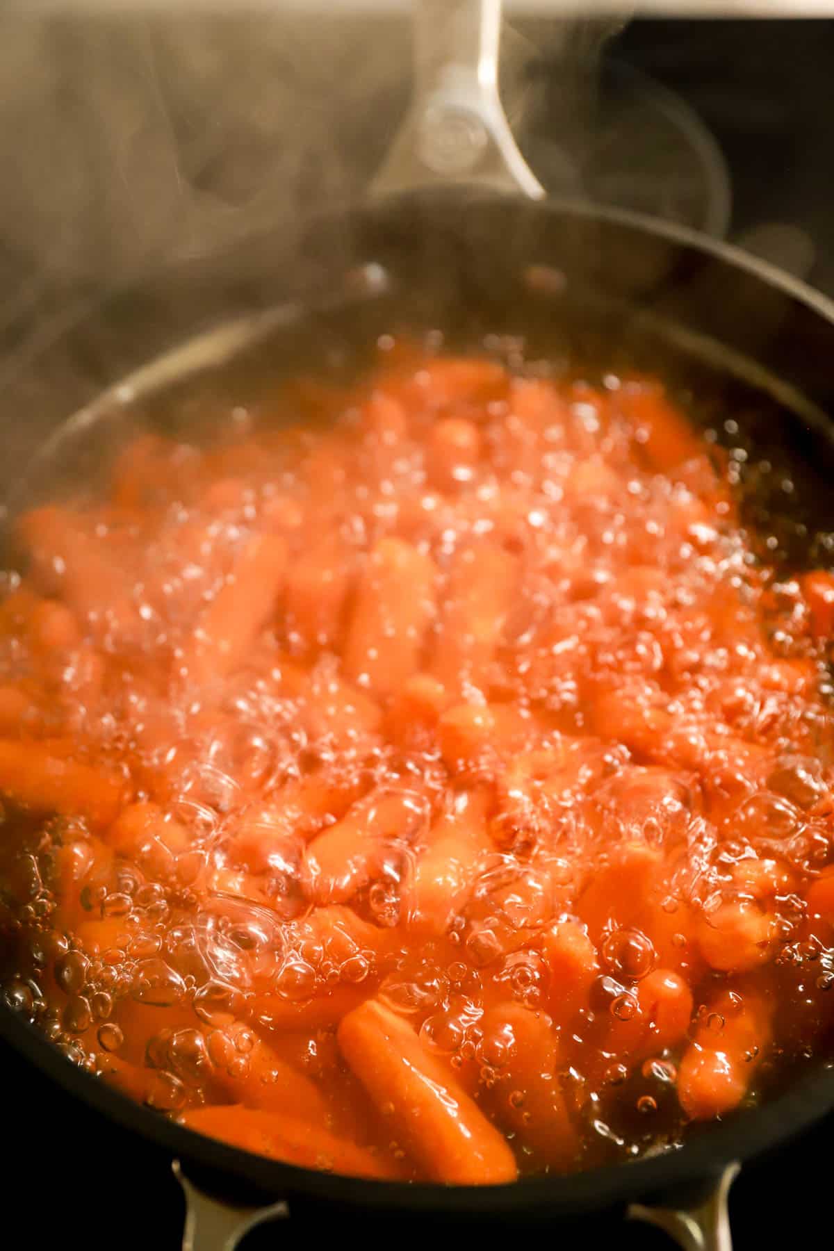 Deep skillet of boiling baby carrots.