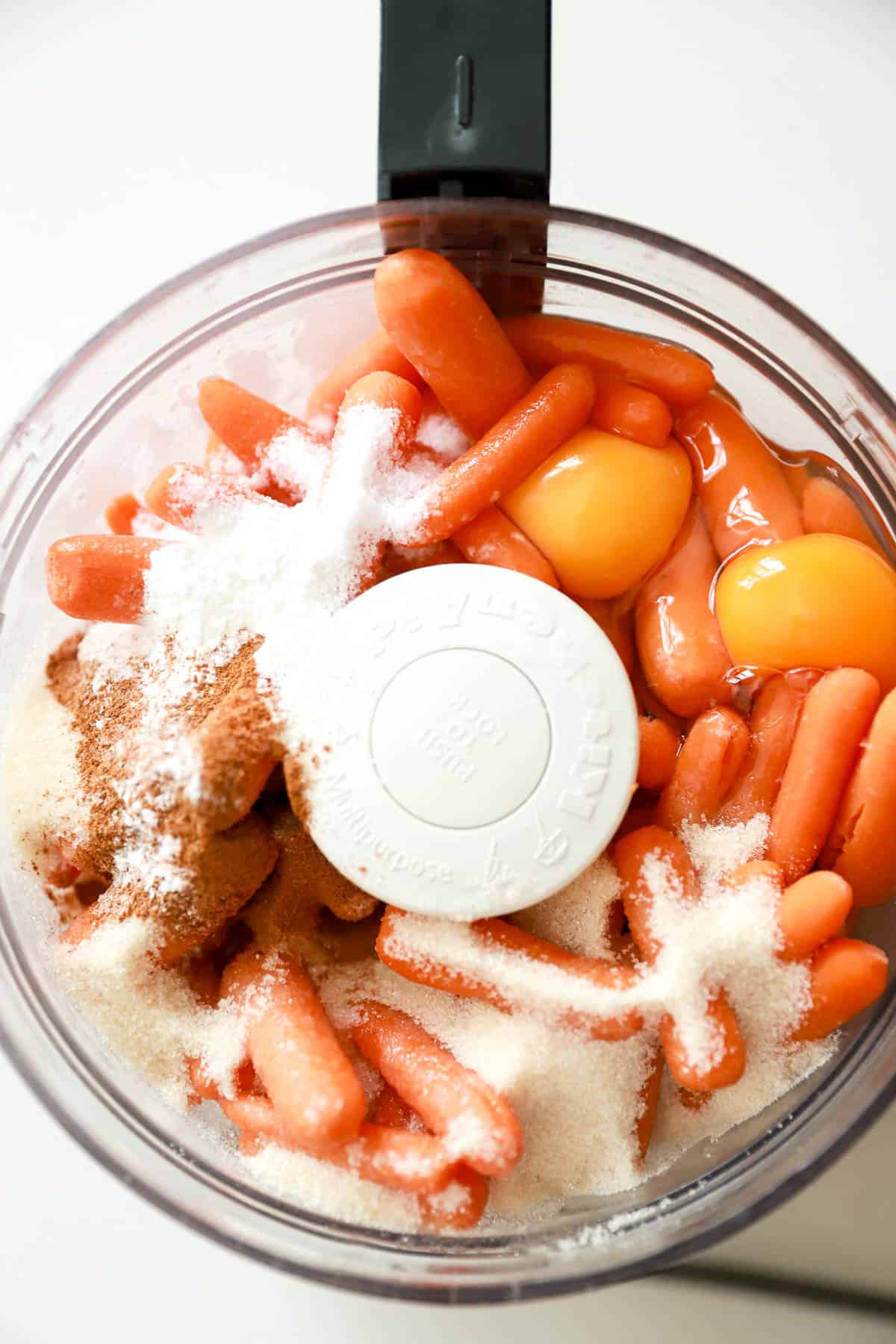 Ingredients for carrot souffle in the bowl of a food processor.