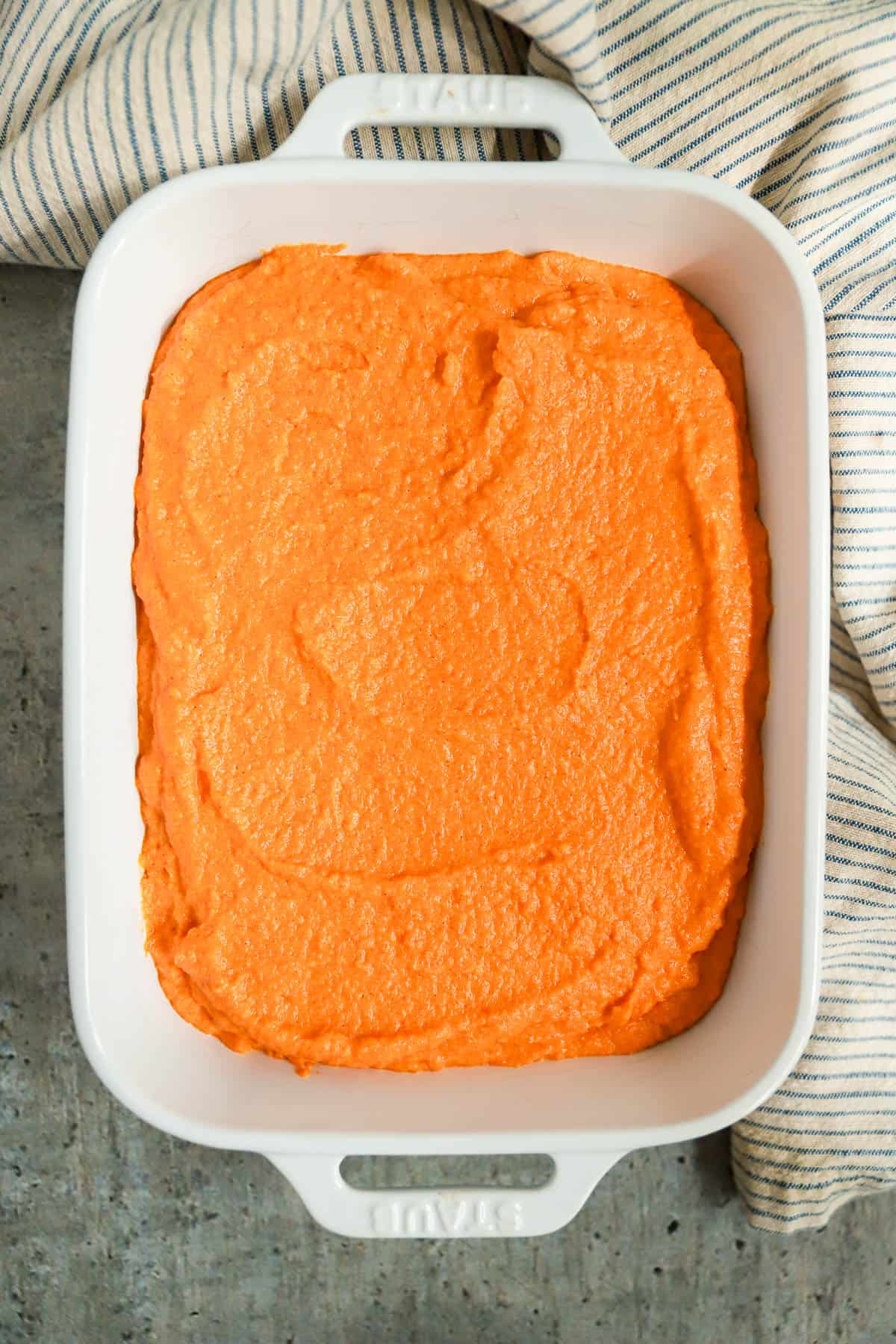 Carrot souffle spread in a white baking dish, unbaked and without topping.