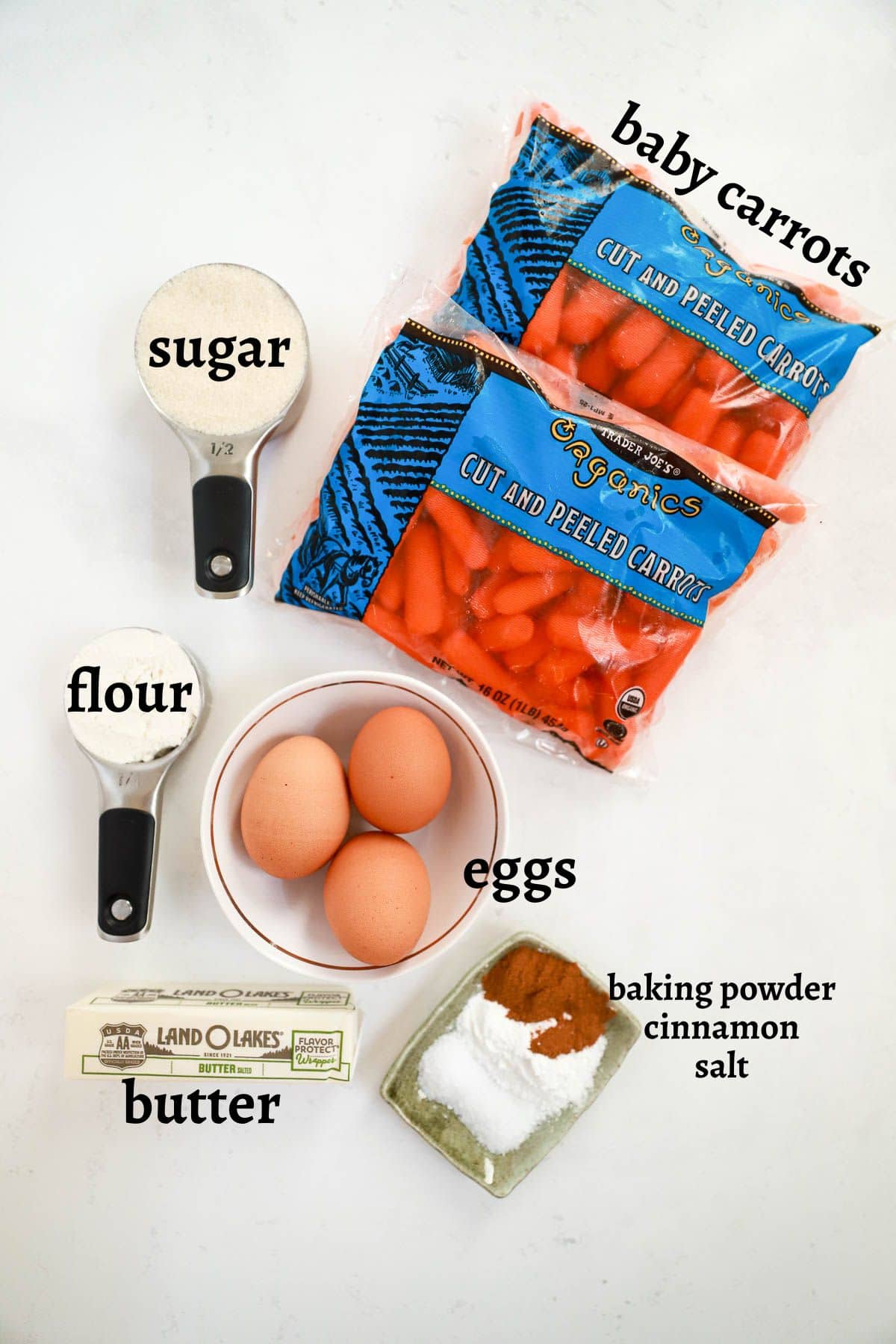 Ingredients for carrot souffle labeled with text on a white table.